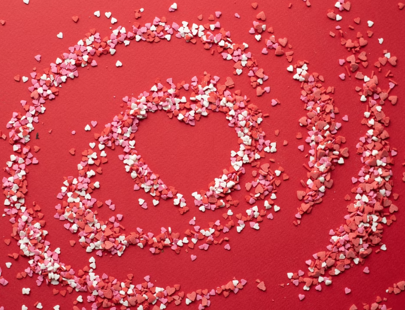 Spiral of pink red and white sugar hearts on a red background